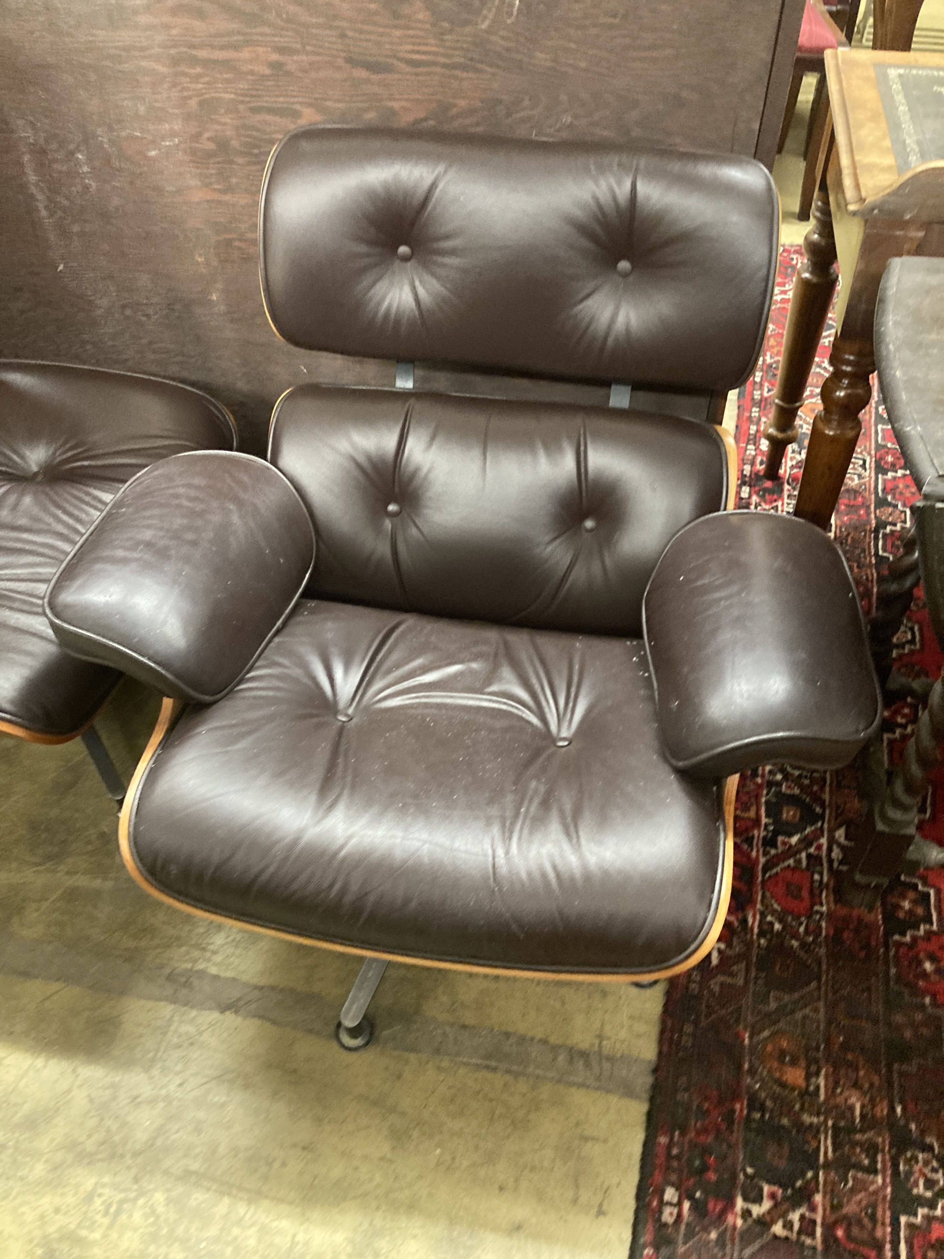 An Eames style modern buttoned dark brown leather swivel chair, width 92cm, depth 74cm, height 78cm and matching stool